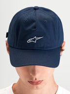 Alpinestars Casquette Dad Dylan, casquette sportswear décontractée bleue portée par un modèle, en sergé de coton avec visière courbée et logo Astars brodé en blanc à l'avant