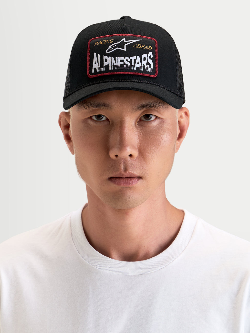 Alpinestars Casquette Trucker Hemmings, casquette sportswear noire avec visière incurvée et arrière en mesh respirant, dotée d'un écusson tissé avec le logo Alpinestars sur le devant, portée par un modèle