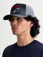 Alpinestars Gravel Trucker Hat, On-Model Casual Sportswear Cap, Dark Gray and Black with Light Gray Mesh Back, Featuring a Structured Crown, Curved Bill, and Woven Front Patch with Red Alpinestars Text, Ideal for Everyday Motorsports-Inspired Style