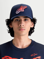 Alpinestars Casquette Trucker Meteorite, casquette sportswear avec arrière en maille pour homme et femme, bleu marine avec logo Astars rouge et blanc à texture gravier, couronne structurée, visière incurvée, vue de face sur un modèle