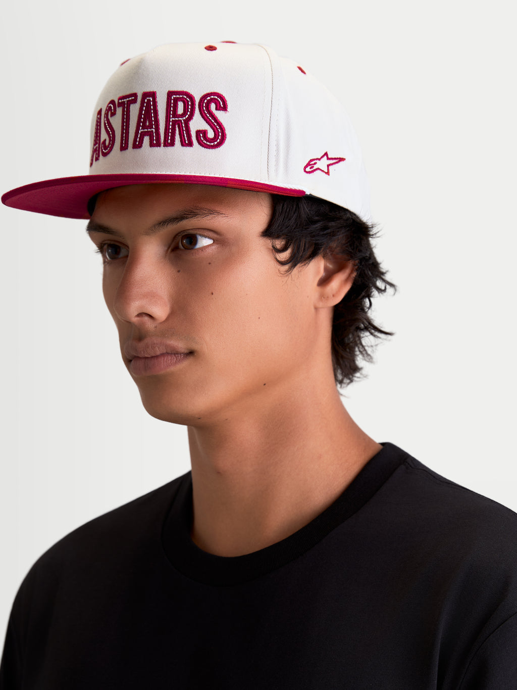 Alpinestars Stadium Snapback, casquette de sportswear, blanc cassé et rouge, visière plate, couronne structurée, applique logo Astars à l'avant avec surpiqûres contrastées et broderie latérale, vue portée.