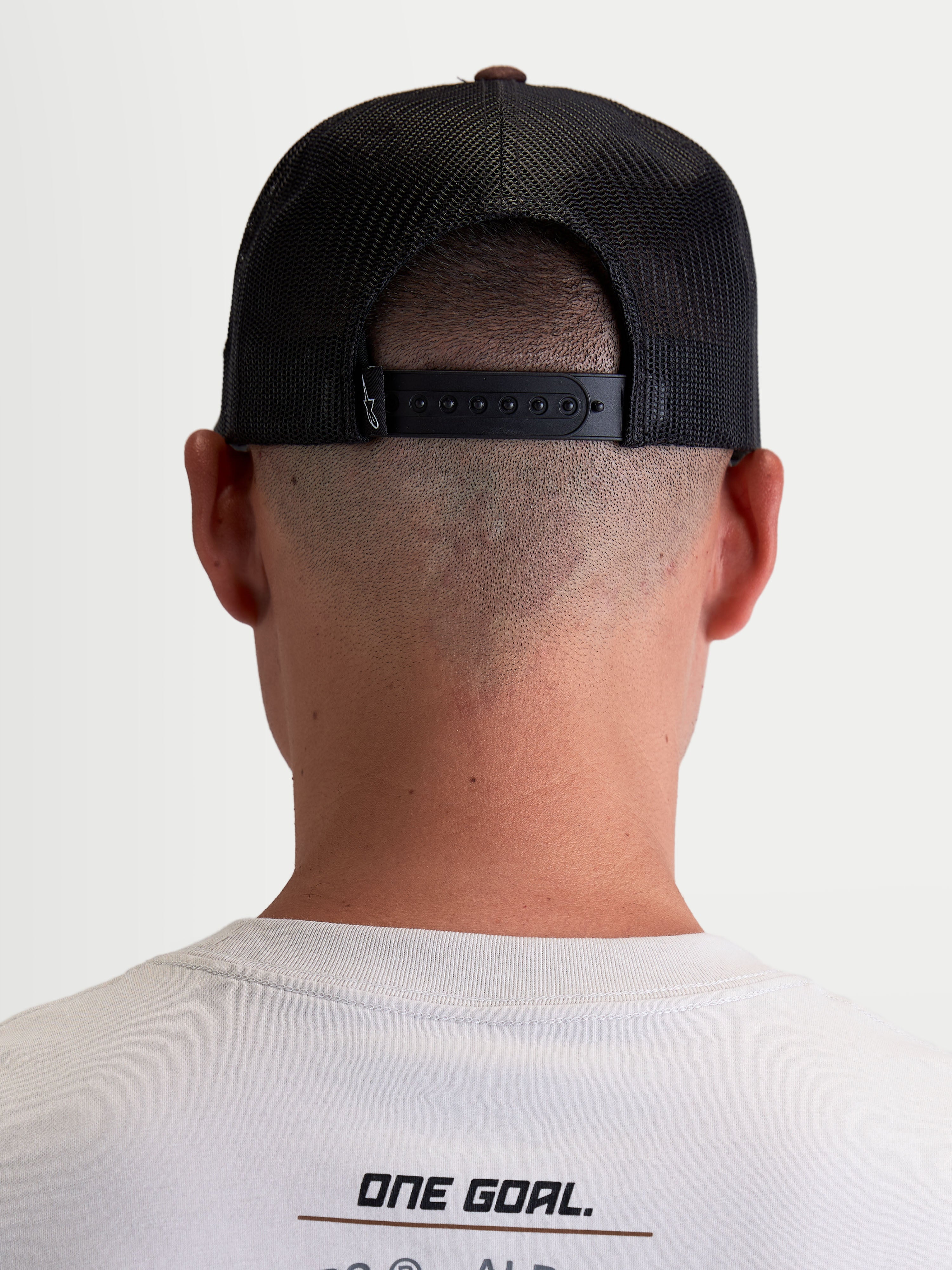 Alpinestars Hotlink Trucker pet, sportswear lifestyle pet, unisex, bruin en zwart, achteraanzicht op model met verstelbare snapback-sluiting, mesh panelen voor ademend vermogen en premium merkdetails.