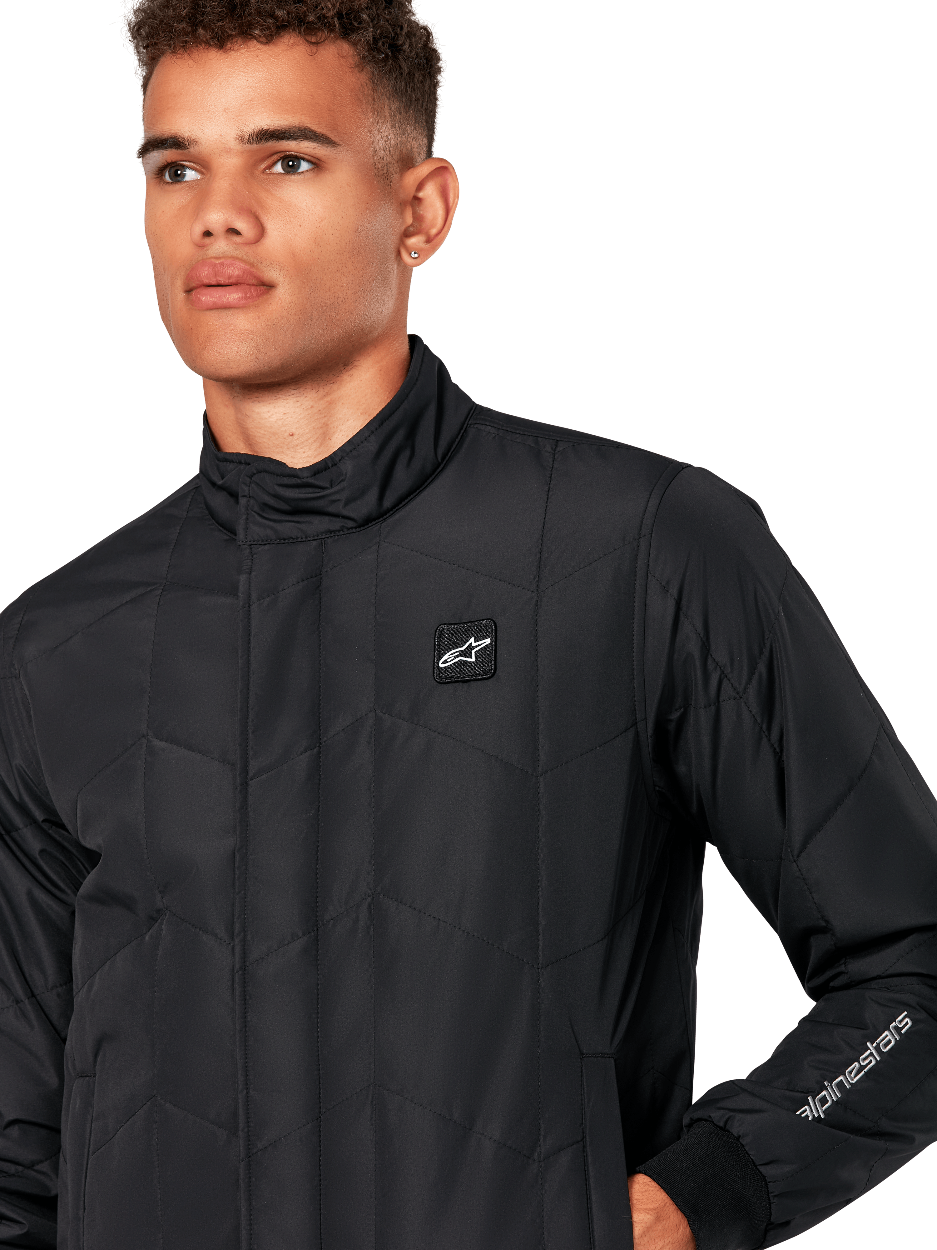 Alpinestars Precedent jas, gestept sportjack voor heren in het zwart, close-up van de lage kraag, logopatch op de borst en het borduursel op de mouw, met een iconisch schuin gestikt patroon voor een op de motorsport geïnspireerde look.