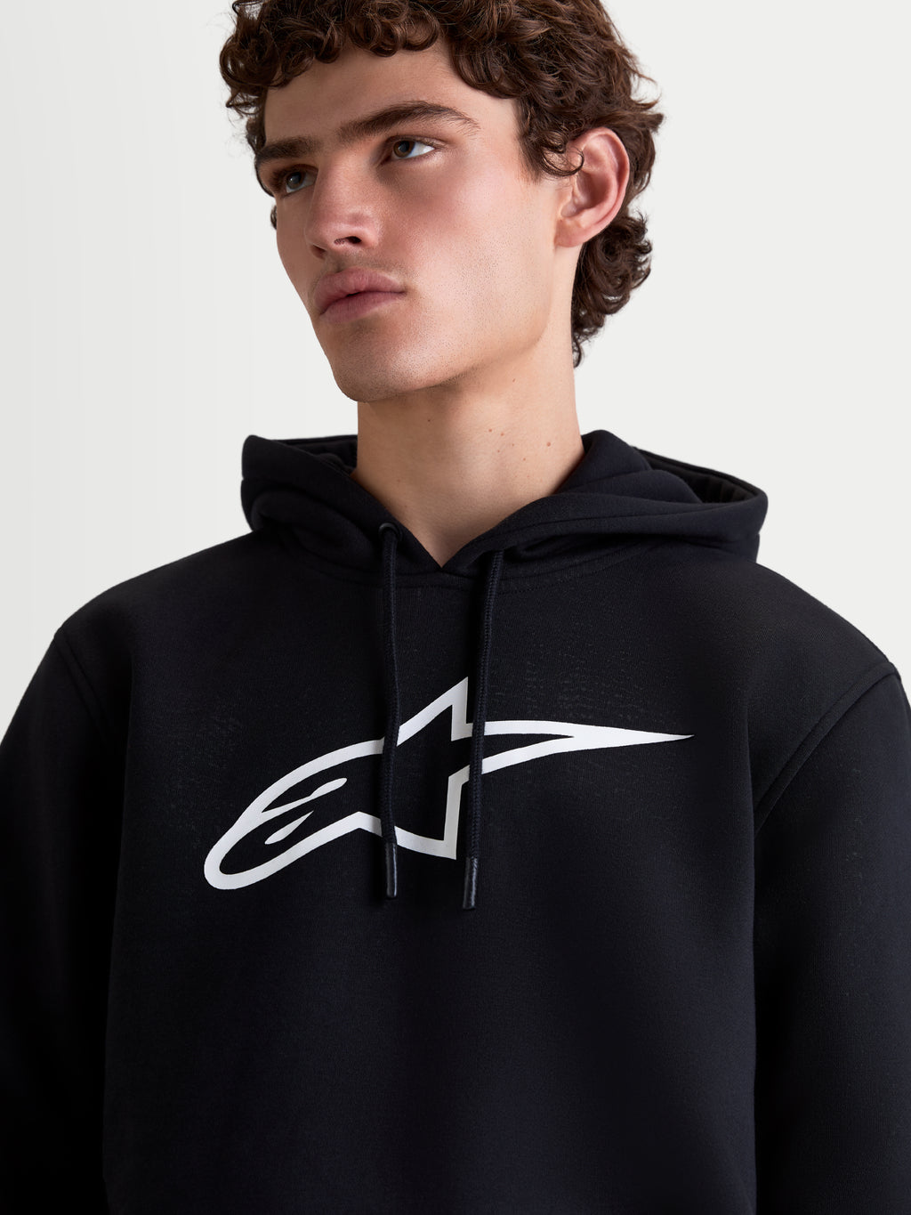 Alpinestars sweat à capuche Ageless V3, sweat sportswear en polaire pour homme, noir et blanc, vue rapprochée avec grand logo blanc sur la poitrine et capuche à cordon de serrage