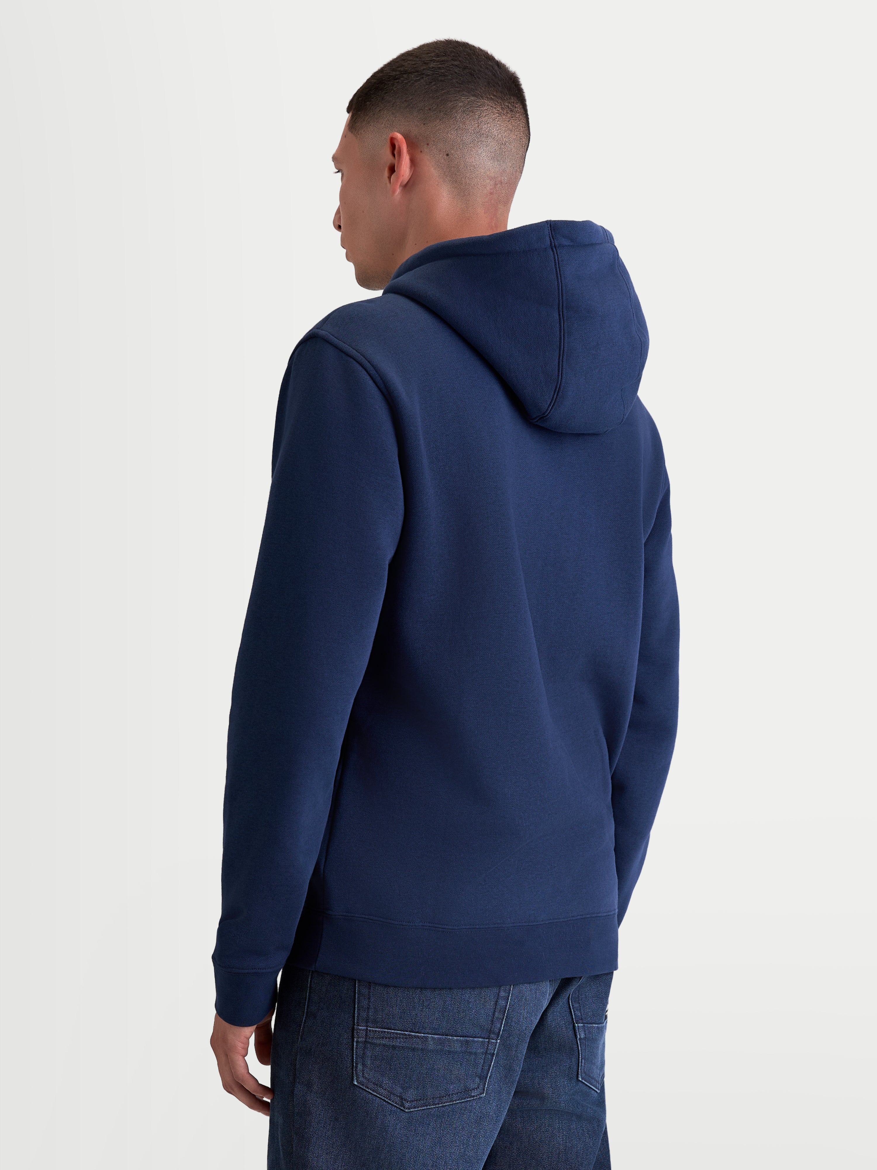 Alpinestars Ageless V3 hoodie, casual sportswear-pulloverfleece, marineblauw, achteraanzicht op model, voorzien van een gevoerde capuchon en geribde manchetten en zoom, premium katoen en gerecycled polyester.