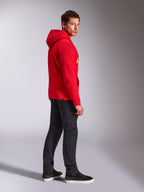 Alpinestars Linear Wordmark V3 Hoodie, rood, casual streetwear, model van de zijkant en achterkant gezien in een rode pullover hoodie met gele logo's, donkergrijze jeans en zwarte sneakers, studio lifestyle-opname