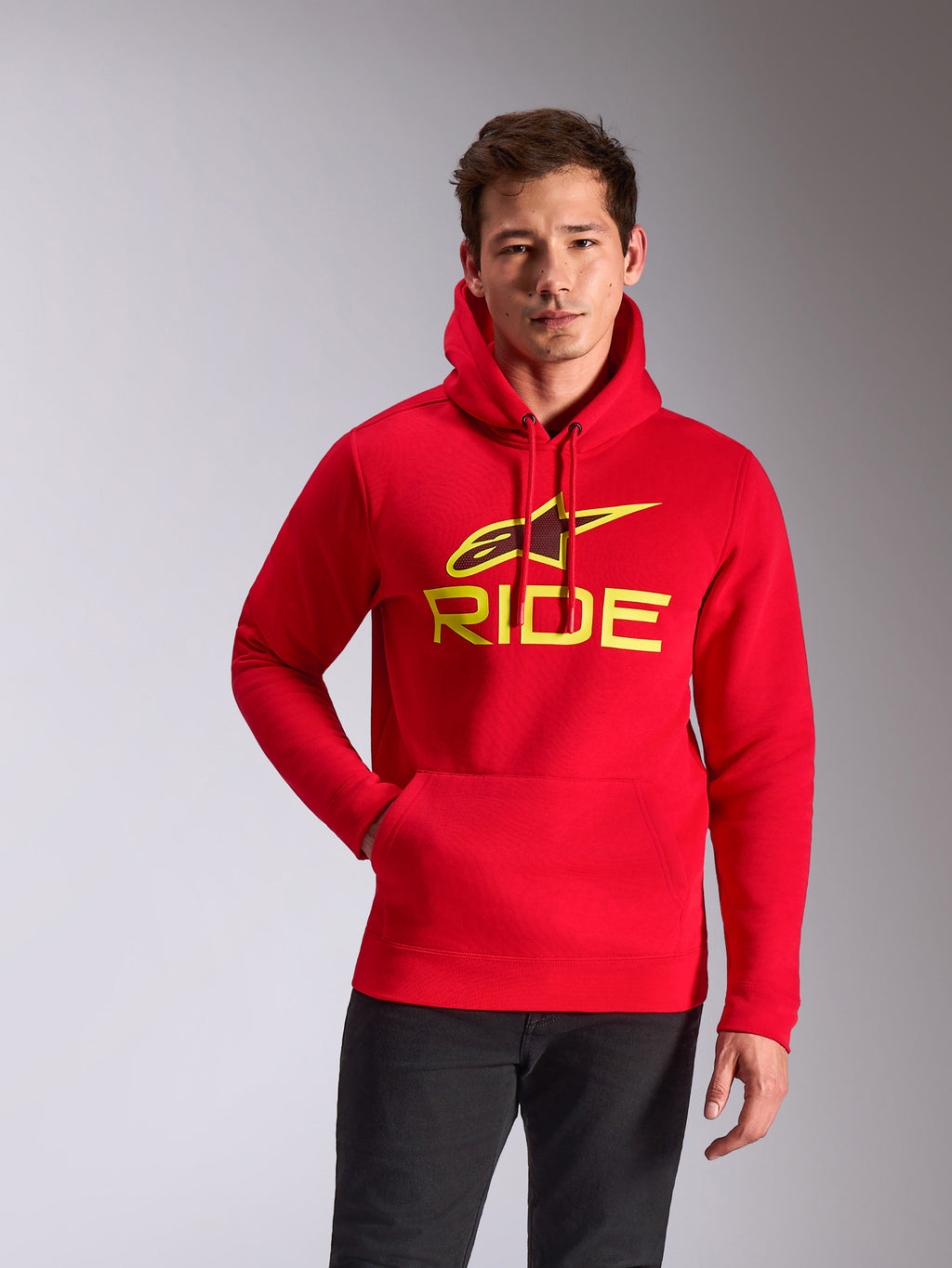 Alpinestars Ride V3 Hoodie, rood met Hi-Vis geel logo, pullover fleece hoodie met 'RIDE' en A-star grafische print, kangoeroezak, casual motorsport streetwear, model draagt de rode hoodie