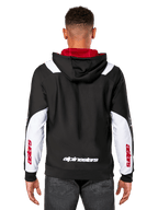 Sweat à capuche Alpinestars Sessions V3, vue de dos, noir avec empiècements blancs sur les manches et doublure de capuche rouge, avec logo textuel blanc au dos et marquage rouge sur les manches, vêtement urbain décontracté inspiré du sport automobile