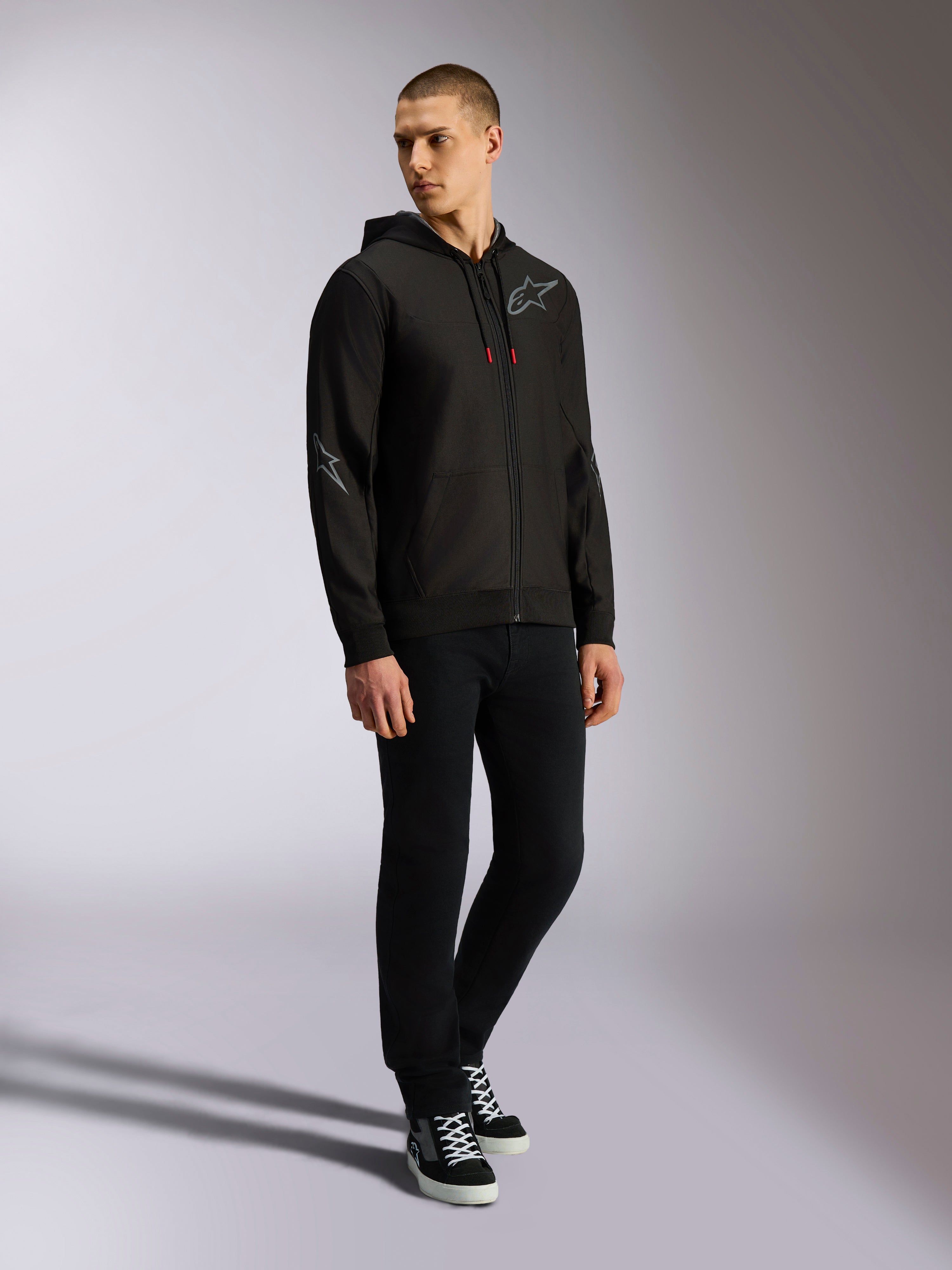 Alpinestars Sessions V3 Hoodie, polyfleece met rits aan de voorkant, zwart en grijs, grijze logo's op de borst en mouwen, capuchon met trekkoord met rode uiteinden, volledige weergave van model in casual motorsport streetwear