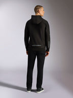 Alpinestars Sessions V3 Hoodie, casual streetwear, zwart met grijs Alpinestars woordmerk op de onderrug en 'astars' branding op de mouwen, achteraanzicht van mannelijk model in hoodie en zwarte broek, modern op de motorsport geïnspireerd ontwerp
