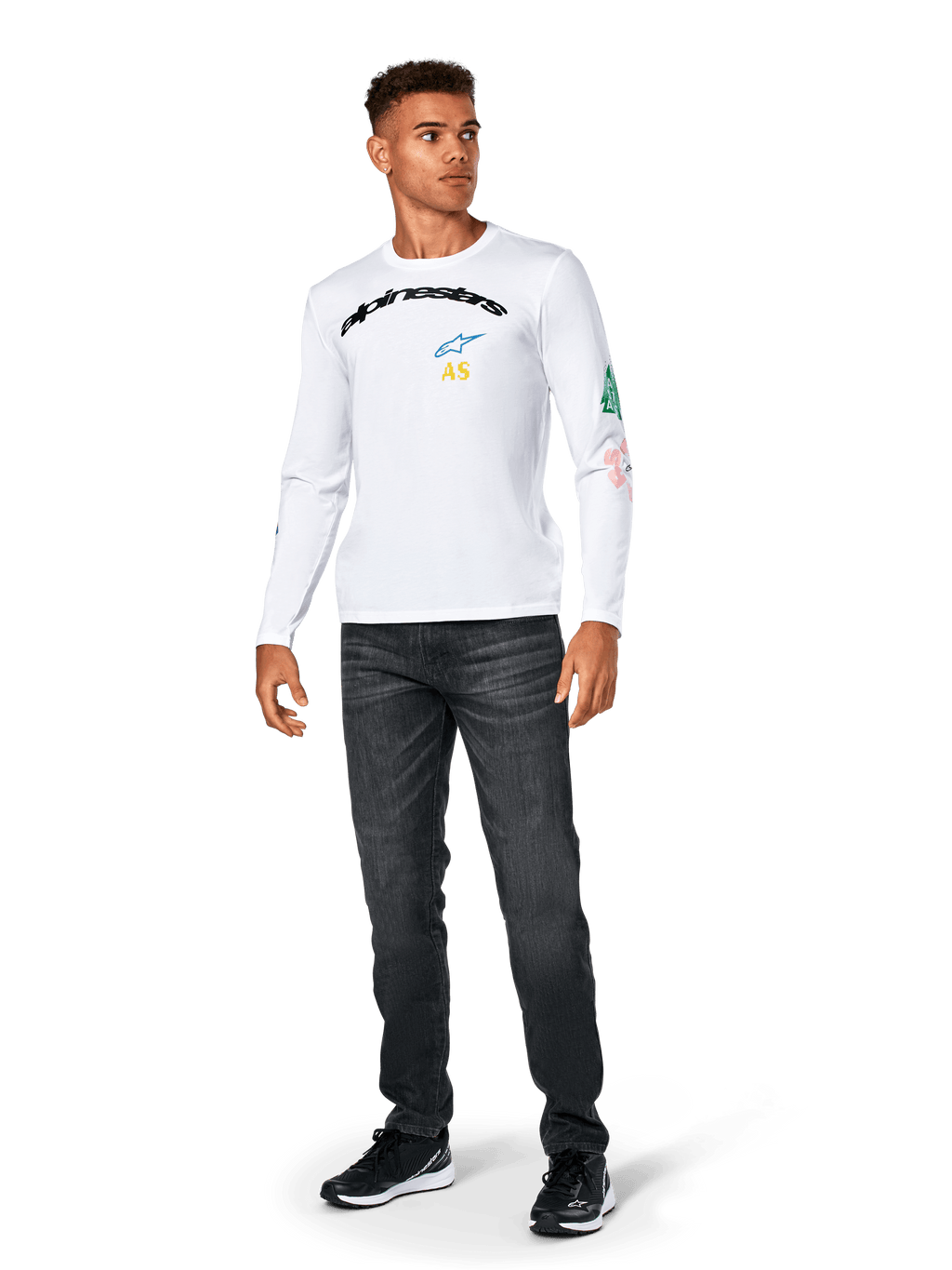 Alpinestars Brundo CSF Tee - lange mouwen, wit, casual sportkleding, voorzien van zwarte 'alpinestars' tekst op de borst, een blauw sterlogo en gele 'AS' initialen, kleurrijke graphics op de mouw, gedragen met donkere jeans en zwarte sneakers.