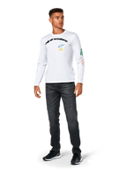 Alpinestars Brundo CSF Tee - lange mouwen, wit, casual sportkleding, voorzien van zwarte 'alpinestars' tekst op de borst, een blauw sterlogo en gele 'AS' initialen, kleurrijke graphics op de mouw, gedragen met donkere jeans en zwarte sneakers.