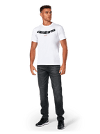 Alpinestars Elliptic CSF Tee, t-shirt à manches courtes, blanc, logo Astars arqué noir avec symbole d'étoile orange, porté par un mannequin avec un jean noir et des baskets, style streetwear motorsport décontracté