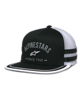 Alpinestars Backline Trucker Hat, schwarze Twill-Vorderseite und weiße Mesh-Rückseite, flacher Schirm mit weißem Soutache-Besatz am Rand, graues bogenförmiges Alpinestars-Logo mit „Since 1963“-Schriftzug, seitliche Applikationsstreifen, lässige vom Motorsport inspirierte Snapback-Kappe