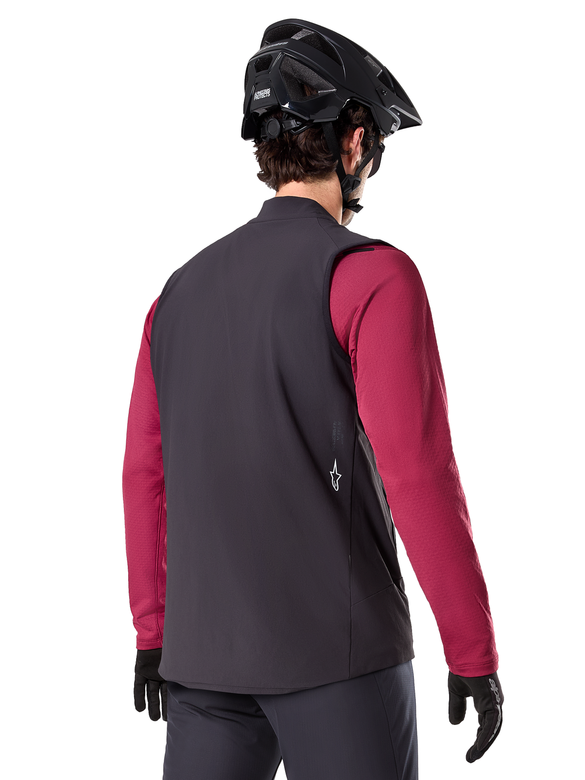 Gilet thermique Alpinestars A-Dura, noir, vue de dos, porté sur un maillot à manches longues bordeaux avec un casque de VTT et des gants noirs, équipement de cyclisme léger et isolé pour le tout-terrain