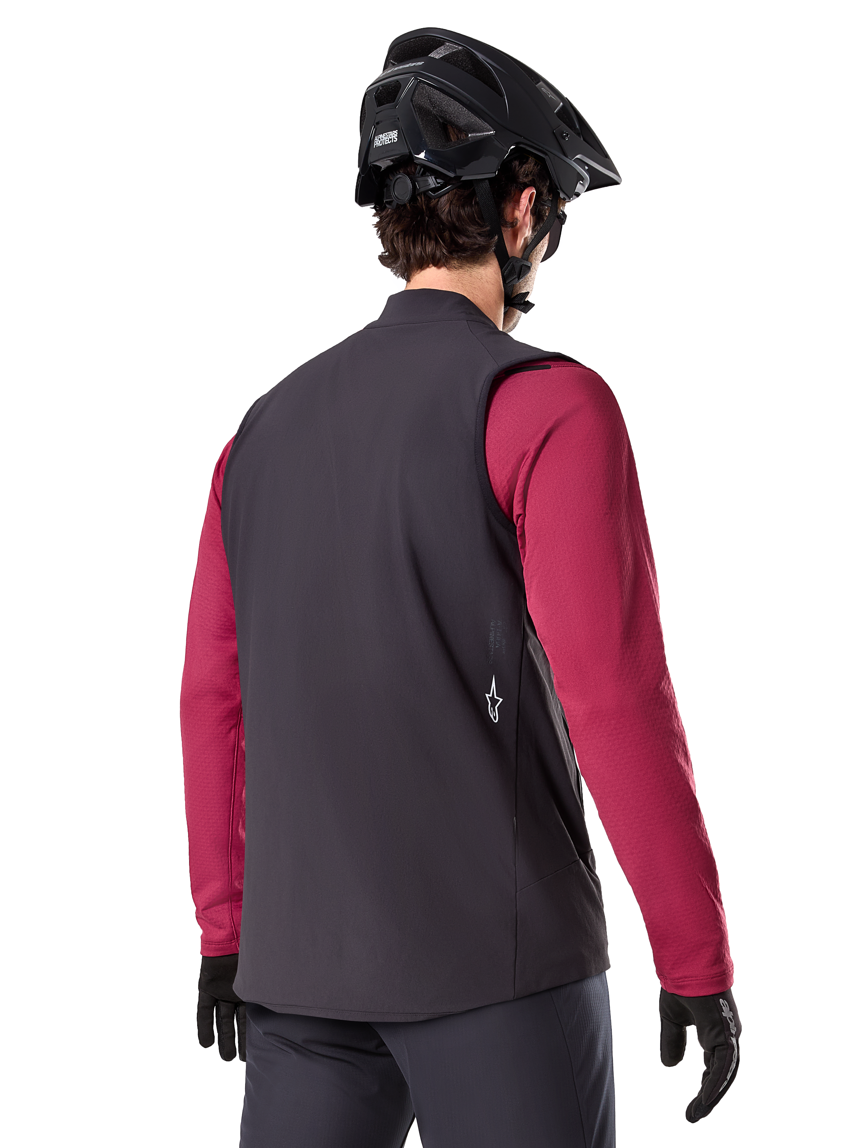 Gilet thermique Alpinestars A-Dura, noir, vue de dos, porté sur un maillot à manches longues bordeaux avec un casque de VTT et des gants noirs, équipement de cyclisme léger et isolé pour le tout-terrain