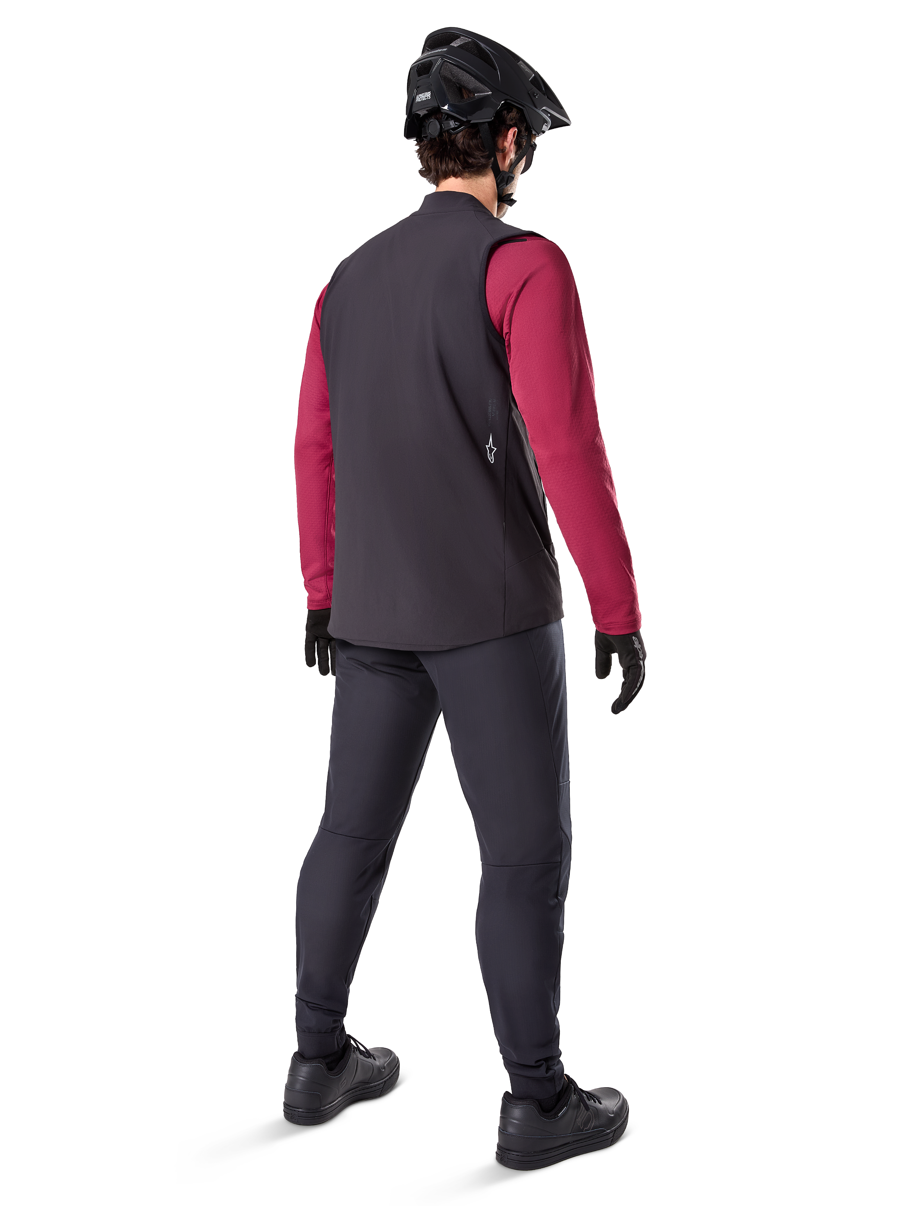 Gilet thermique Alpinestars A-Dura, gilet de cyclisme noir, vu de dos sur un modèle portant un maillot à manches longues bordeaux et un pantalon de cyclisme noir, associé à un casque de VTT et des gants noirs, équipement technique pour rouler par temps froid