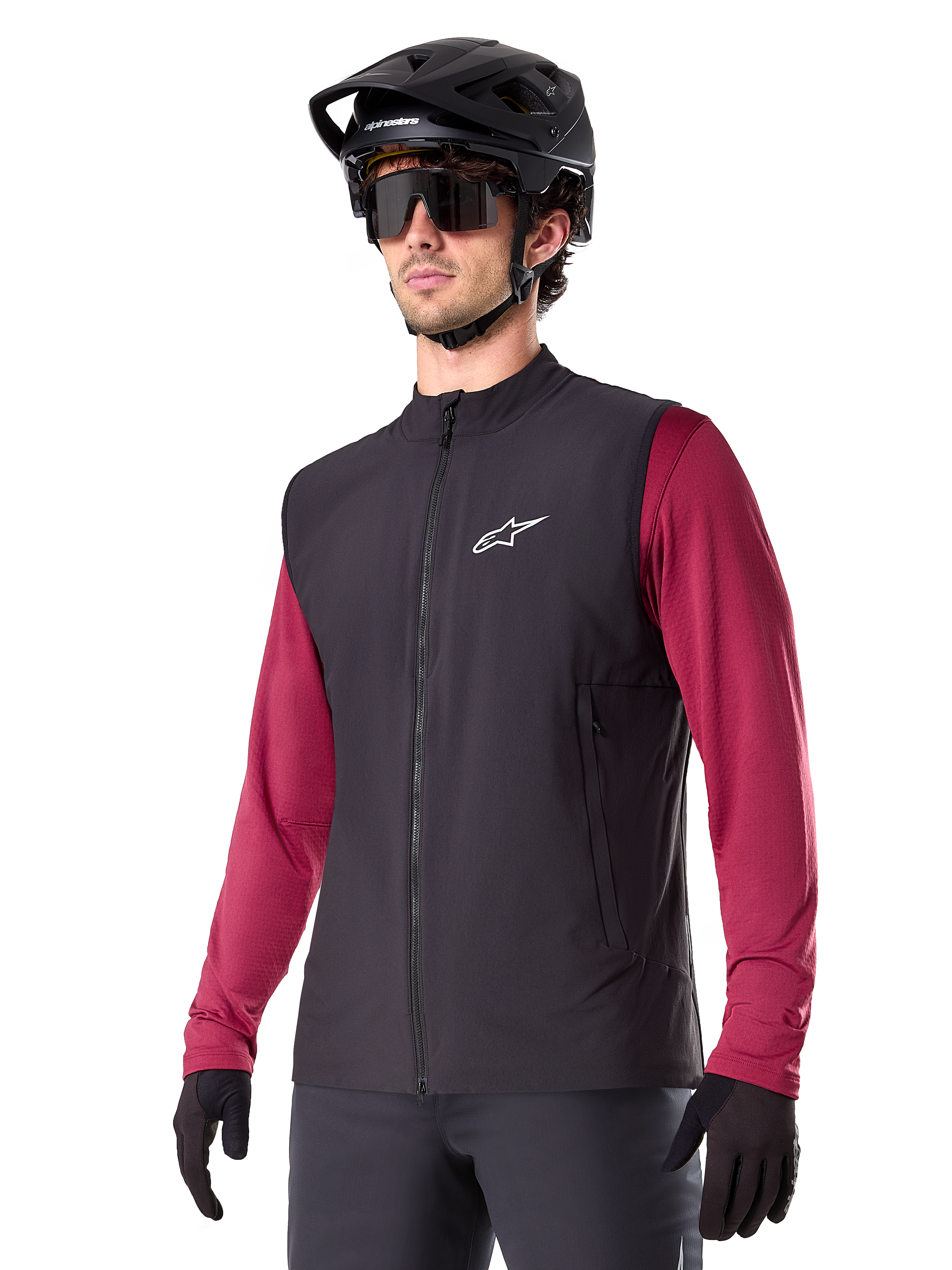 Gilet thermique Alpinestars A-Dura, noir, gilet thermique de cyclisme, porté sur un maillot à manches longues bordeaux, avec un logo blanc sur la poitrine, associé à un casque de VTT noir et des lunettes de soleil, couche de performance isolante pour le VTT