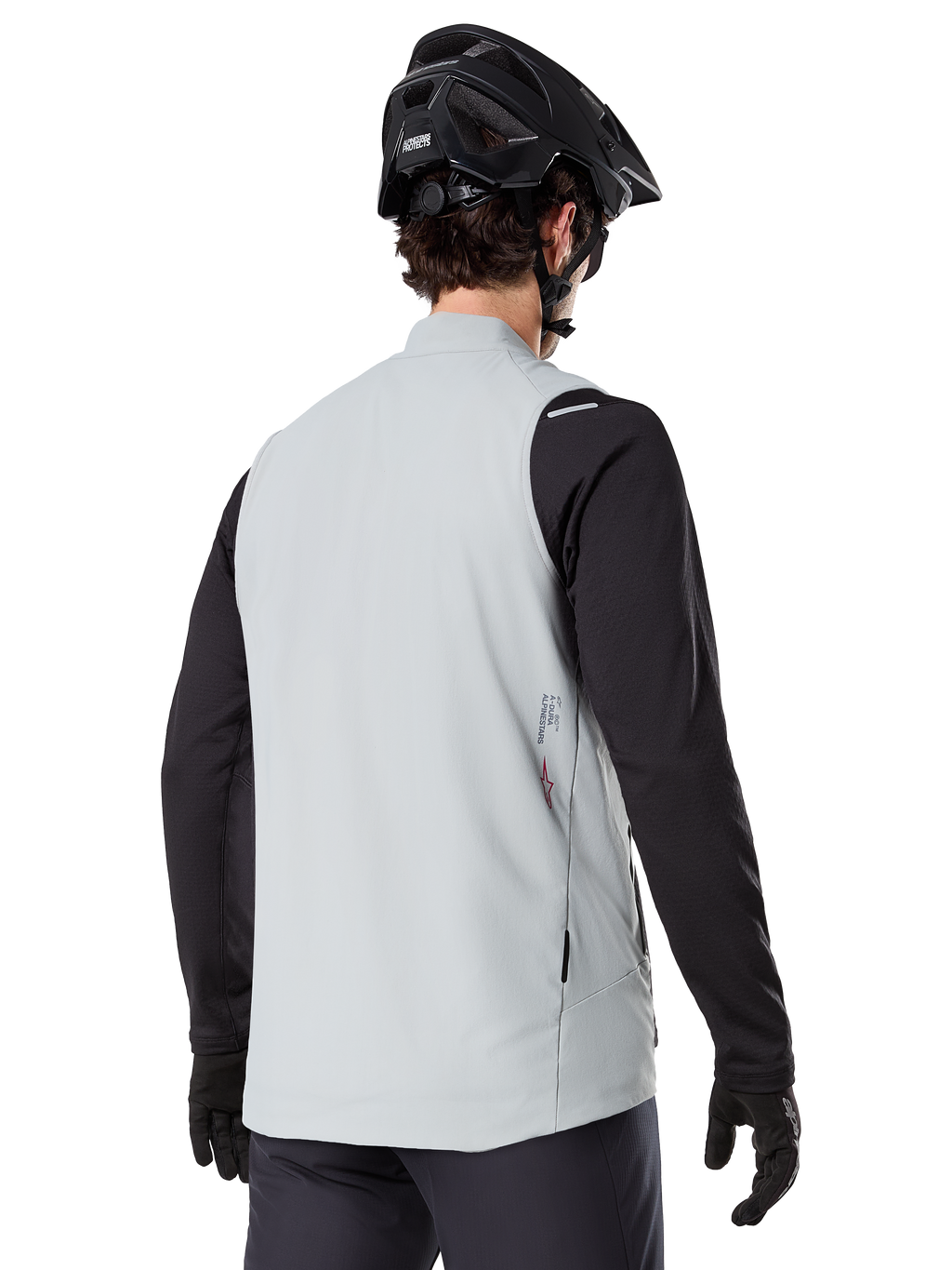 Gilet thermique Alpinestars A-Dura, Gris titane, vue arrière d'un modèle portant un maillot noir à manches longues et un casque de VTT, design minimaliste avec un petit logo étoile rouge au dos, gilet de cyclisme léger et isolant pour le tout-terrain