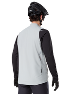 Gilet thermique Alpinestars A-Dura, Gris titane, vue arrière d'un modèle portant un maillot noir à manches longues et un casque de VTT, design minimaliste avec un petit logo étoile rouge au dos, gilet de cyclisme léger et isolant pour le tout-terrain