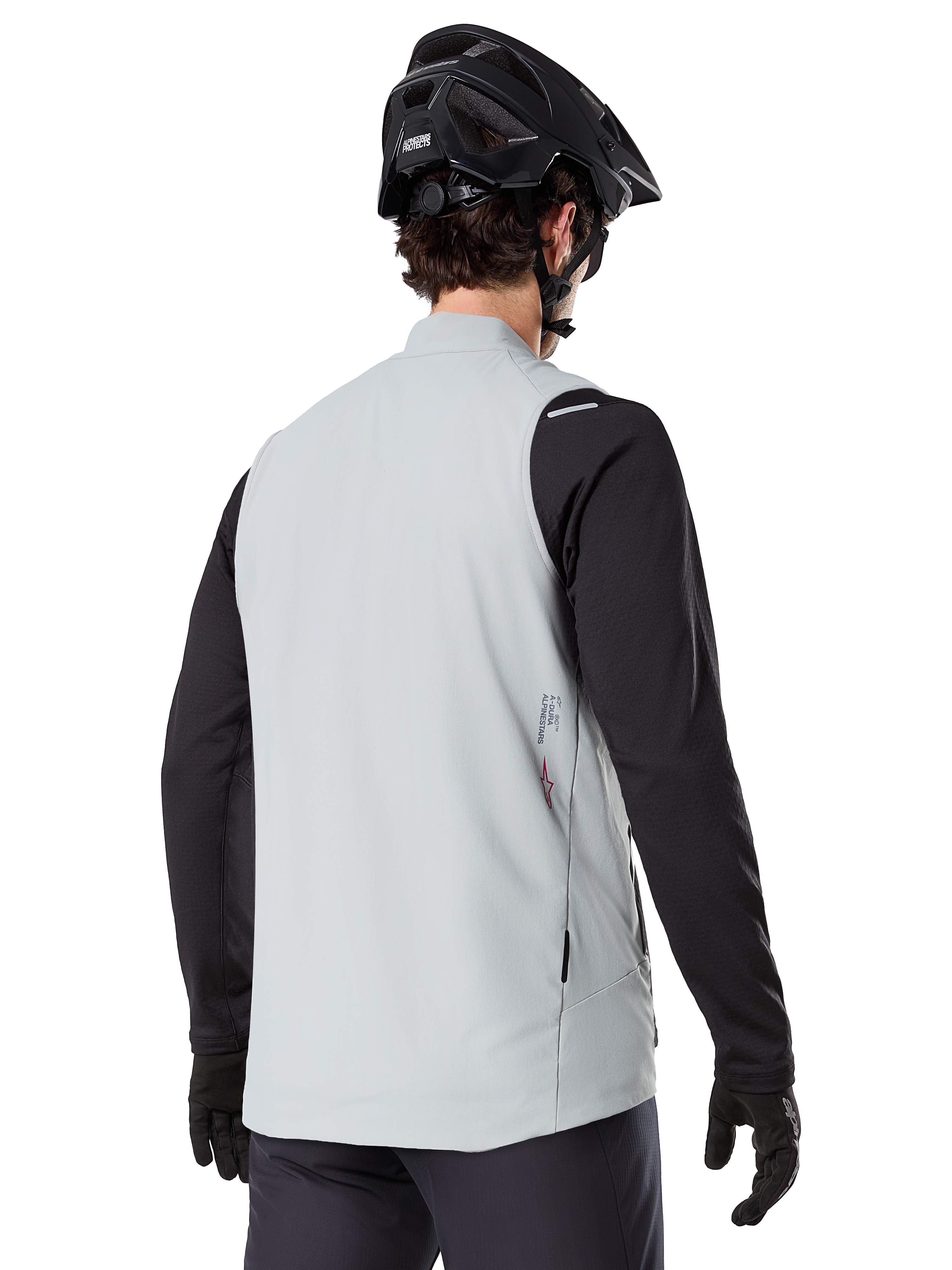 Gilet thermique Alpinestars A-Dura, Gris titane, vue arrière d'un modèle portant un maillot noir à manches longues et un casque de VTT, design minimaliste avec un petit logo étoile rouge au dos, gilet de cyclisme léger et isolant pour le tout-terrain