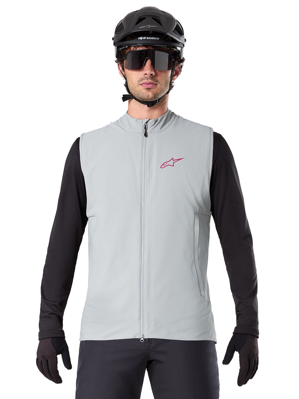 Gilet thermique Alpinestars A-Dura, gilet de cyclisme, gris Titanium, porté avec un maillot noir à manches longues et un casque de cyclisme noir, logo étoile Alpinestars rouge sur la poitrine, léger et isolé pour le VTT