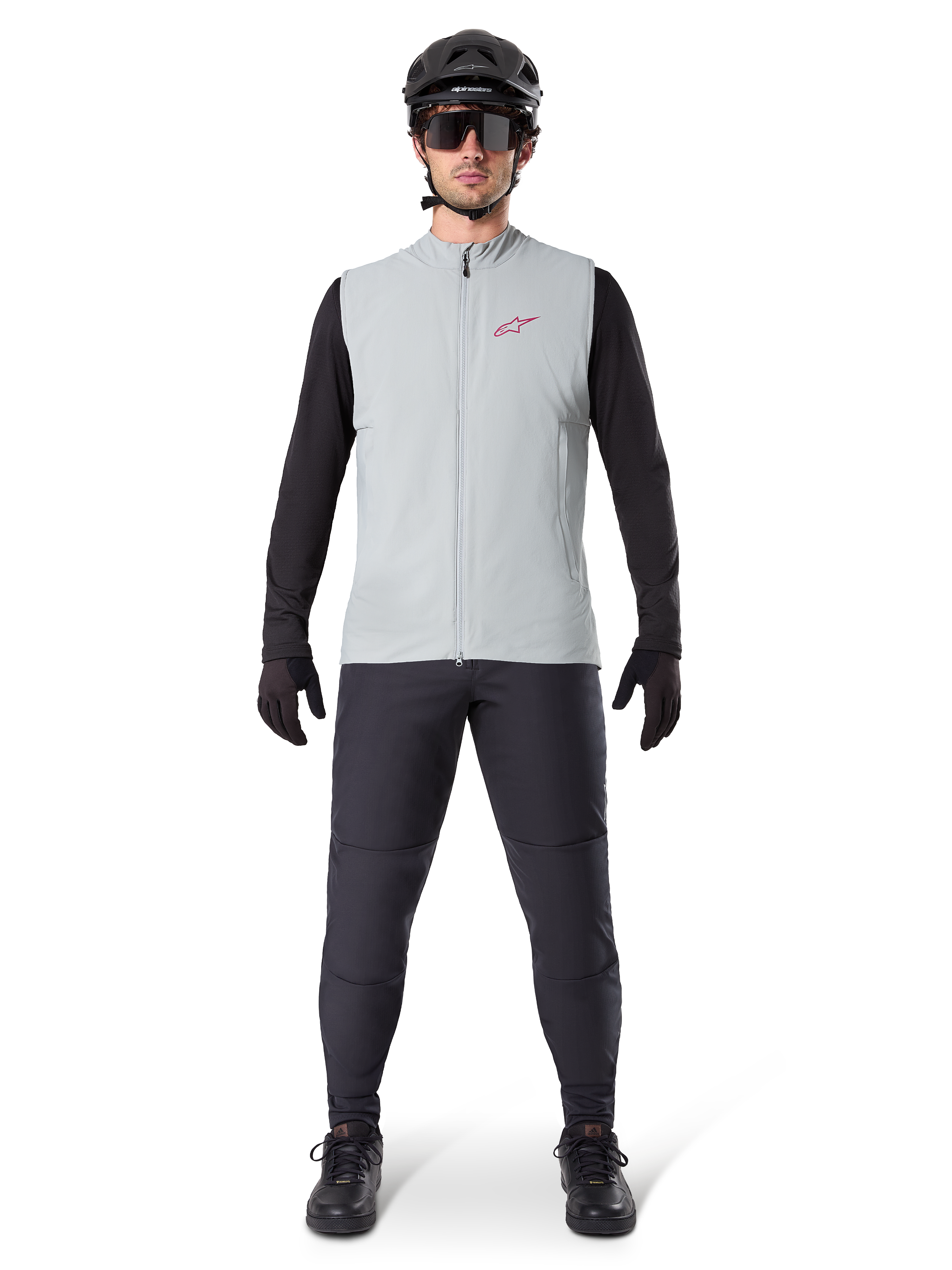 Gilet thermique Alpinestars A-Dura, gilet de cyclisme, gris titane, porté avec un maillot à manches longues noir et un pantalon noir, casque noir et lunettes de soleil, avec un logo Alpinestars rouge, isolation thermique légère pour le VTT