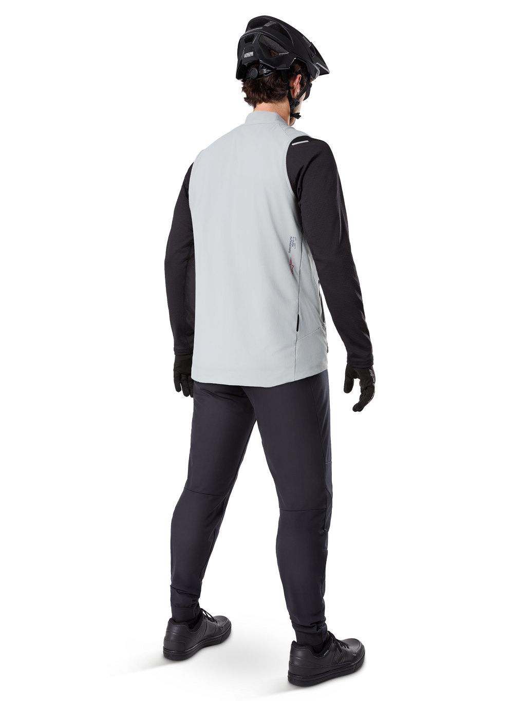 Alpinestars A-Dura Thermal Vest, Gris Titanium, vue arrière d'un mannequin portant le gilet de cyclisme isolant sur un haut noir à manches longues et un pantalon sombre, avec un casque de VTT noir et des gants, conçu pour la conduite tout-terrain par temps froid