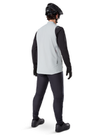 Alpinestars A-Dura Thermal Vest, Gris Titanium, vue arrière d'un mannequin portant le gilet de cyclisme isolant sur un haut noir à manches longues et un pantalon sombre, avec un casque de VTT noir et des gants, conçu pour la conduite tout-terrain par temps froid