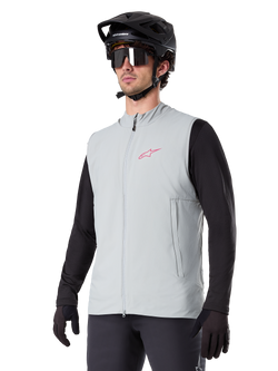 Alpinestars A-Dura Thermal Vest, Titanium Gray, cycling insulated vest, worn over a black long-sleeve shirt with a black mountain bike helmet and gloves, featuring a pink chest logo and vertical zippered side pockets