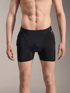 Boxer de Protection Alpinestars A-Motion Plasma, short de protection VTT, noir avec accents Camo noir, vue de face sur un modèle masculin, doté d'une maille extensible respirante et de protections de hanches intégrées pour la performance en cyclisme.