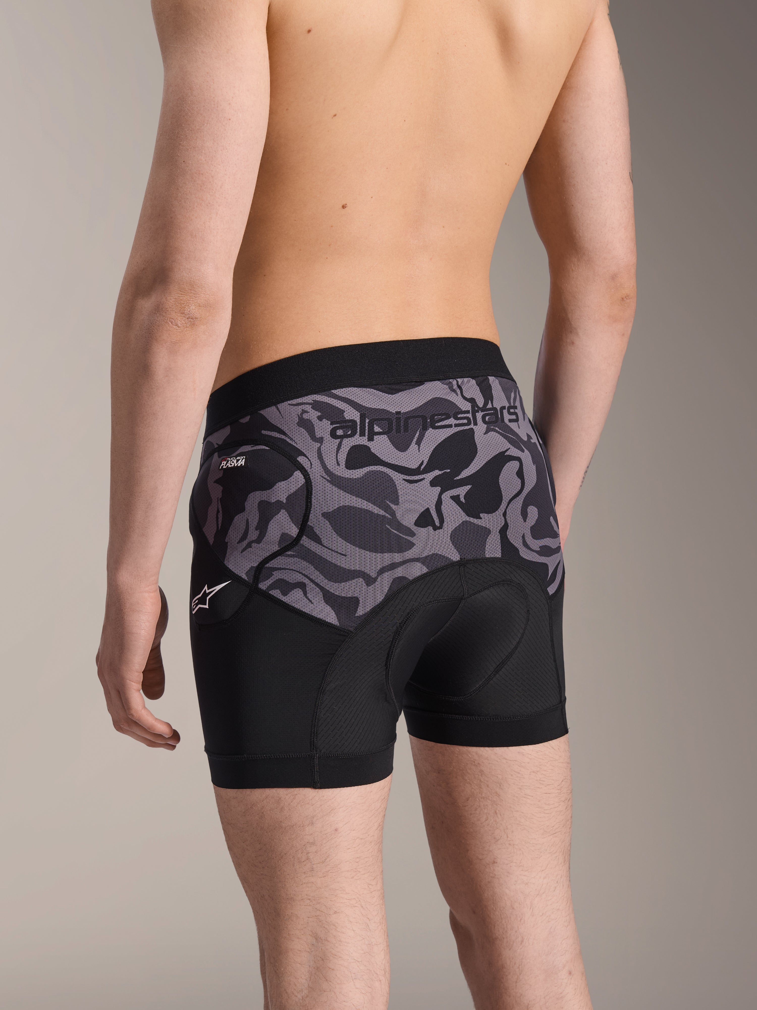 Boxers de Protection Alpinestars A-Motion Plasma, short de protection pour le cyclisme Black Camo, vue arrière montrant le design ergonomique avec protection de hanche Nucleon Plasma et peau de chamois, matériau en maille respirante avec logo Alpinestars sur la ceinture