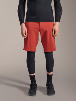 Alpinestars A-Motion Plasma Kniebandage, schwarzer MTB-Knieschützer, getragen mit roten Shorts und schwarzem Langarm-Oberteil, schlankes ergonomisches Design, leichte Mesh-Konstruktion für den Offroad-Einsatz