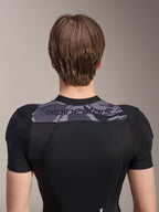 Alpinestars A-Motion Plasma Protection Jacket - korte mouwen, achteraanzicht van het bovenlichaam, zwart met grijs camouflagepaneel over de schouders met Alpinestars-logo, ademende stretch mesh-constructie voor MTB-bescherming
