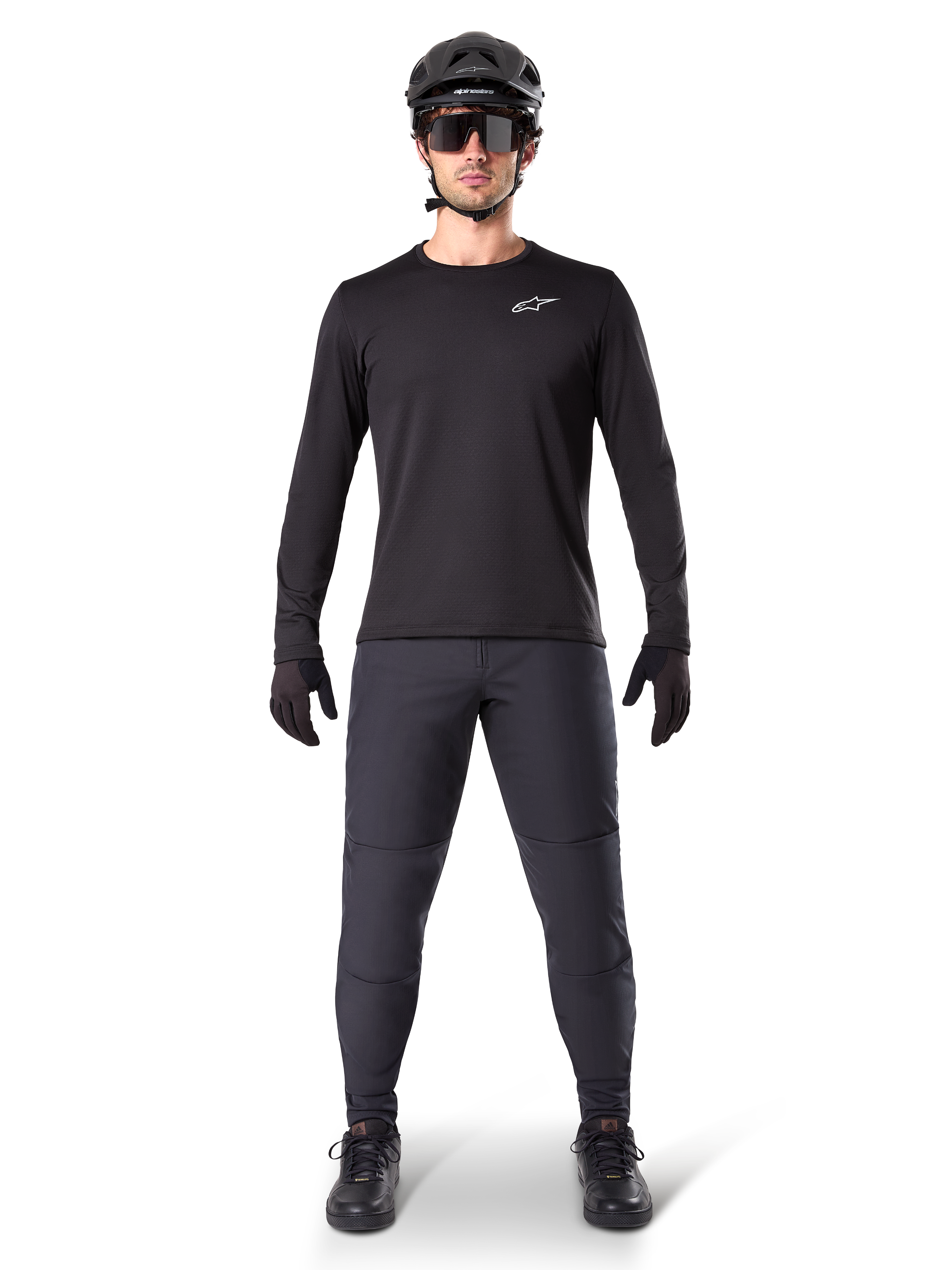 Pantalon thermique Alpinestars A-Dura, noir, porté par un cycliste en tenue complète de VTT avec maillot noir à manches longues, casque et lunettes de soleil, pantalon durable à coupe régulière pour les sorties sur sentier par temps froid