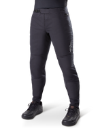 Alpinestars A-Dura Thermal Pant, pantalon de VTT noir, porté avec des chaussures de cyclisme noires, doté d'une fermeture à cliquet à la taille, petit logo blanc sur la cuisse, coupe ajustée pour le cyclisme par temps froid