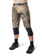 Alpinestars Short A-Dura Camo Liner, short de VTT, motif camouflage marron, vue de face montrant les poches zippées et les ajusteurs de taille latéraux, porté avec des genouillères noires et des chaussures de cyclisme noires, équipement durable pour le VTT