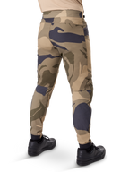 Pantalon Alpinestars A-Dura Camo, pantalon de VTT, motif camouflage marron avec accents beige et gris foncé, vue arrière avec baskets noires, jambes fuselées et chevilles élastiquées, tissu extensible bidirectionnel durable pour le VTT