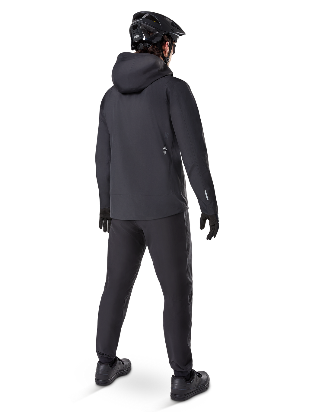 Pantalon imperméable Alpinestars A-Dura, pantalon de VTT, noir, vue de dos sur un cycliste portant une tenue de VTT noire complète avec une veste à capuche et un casque, équipement imperméable durable pour les sentiers boueux