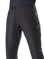 Alpinestars A-Dura Waterproof Pants, pantalon de VTT, noir, gros plan de la taille montrant le système de fermeture à cliquet et les poches zippées, logo Alpinestars blanc sur la cuisse, textile durable pour la pratique du VTT par temps humide