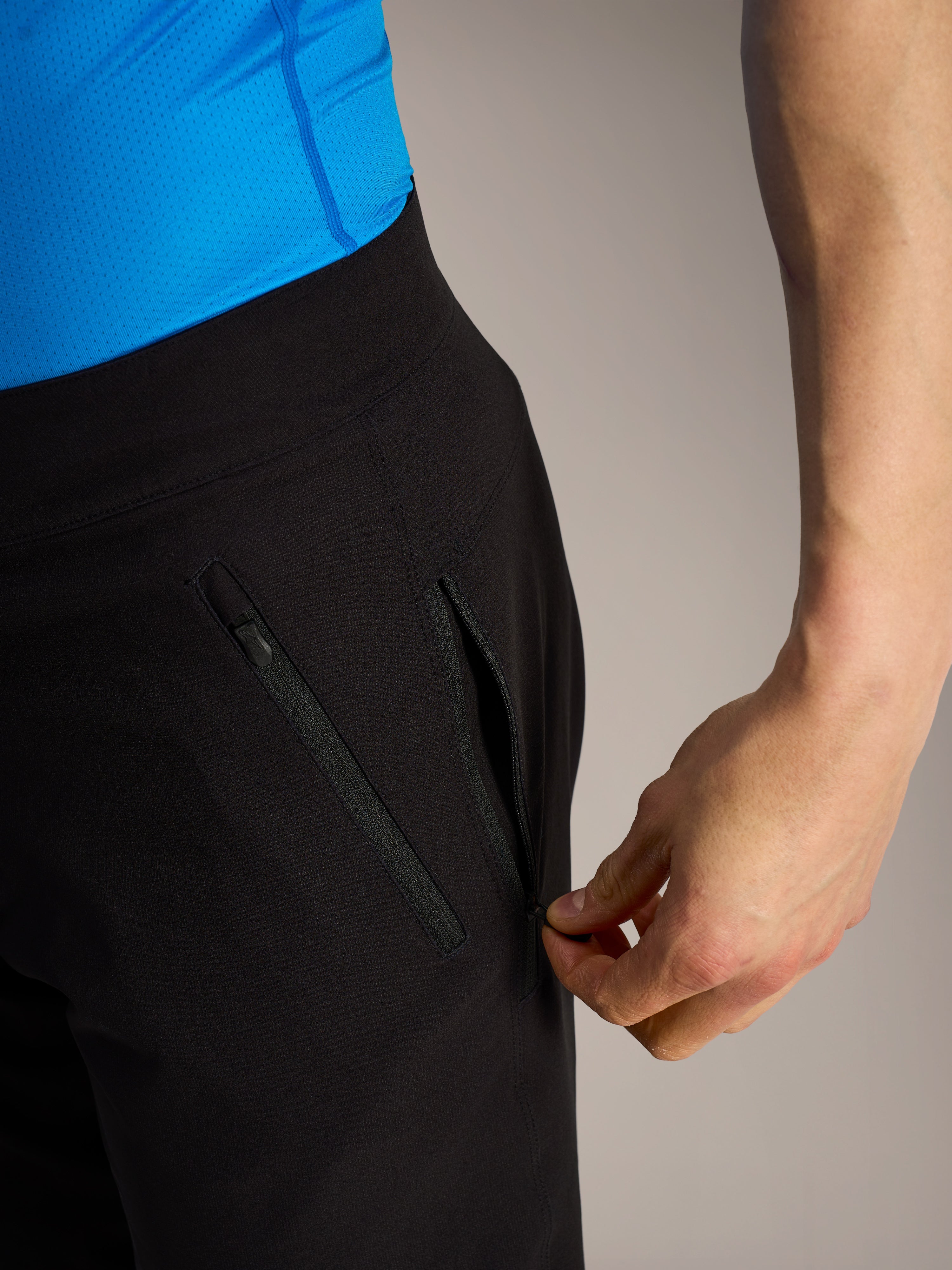 Zwarte Alpinestars A-Dura Ride MTB-shorts, close-up van een hand die een veilige zijzak met rits opent.