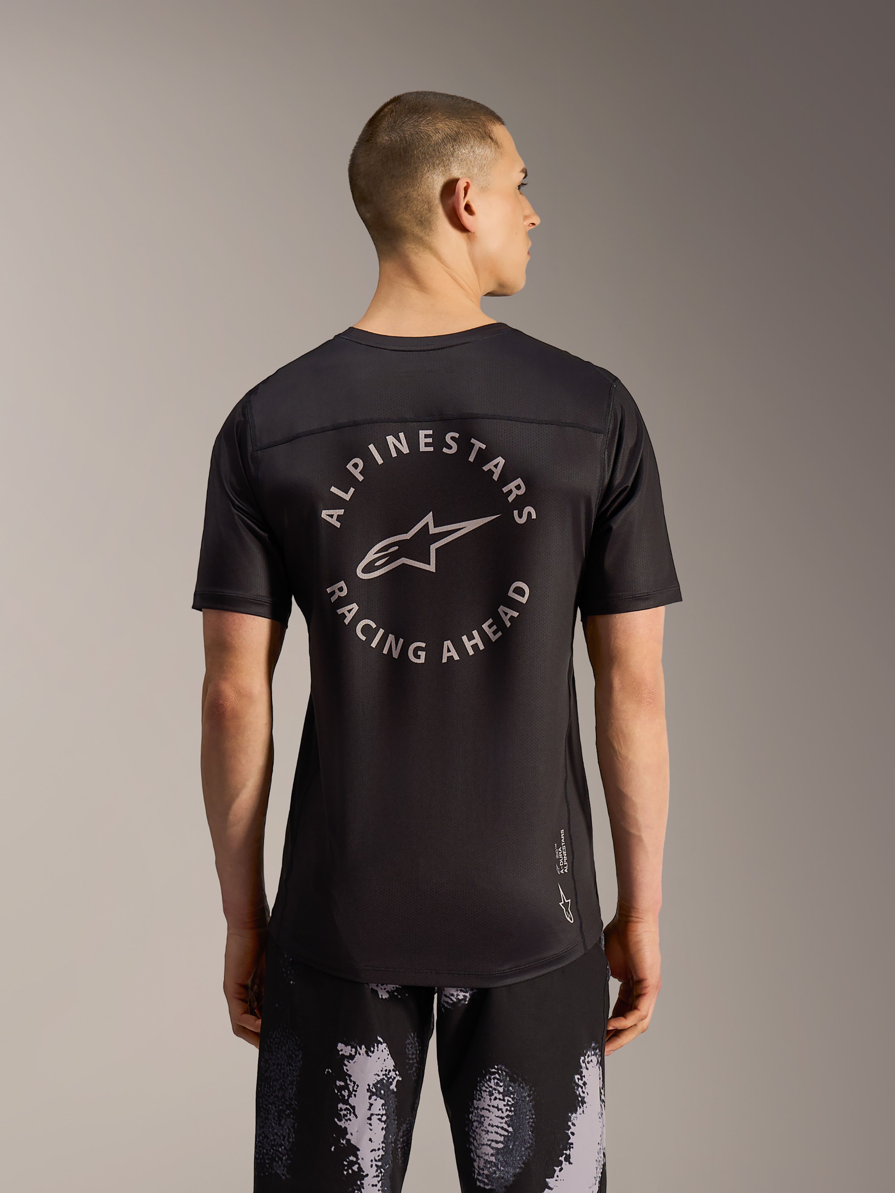 Alpinestars A-Dura Ride MTB-shorts in Black Camo en zwarte MTB-jersey met rond ruglogo, achteraanzicht op een model.