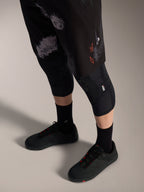 Alpinestars A-Dura Ride MTB-short in Black Camo met oranje logo, gedragen met kniebeschermers en fietsschoenen.