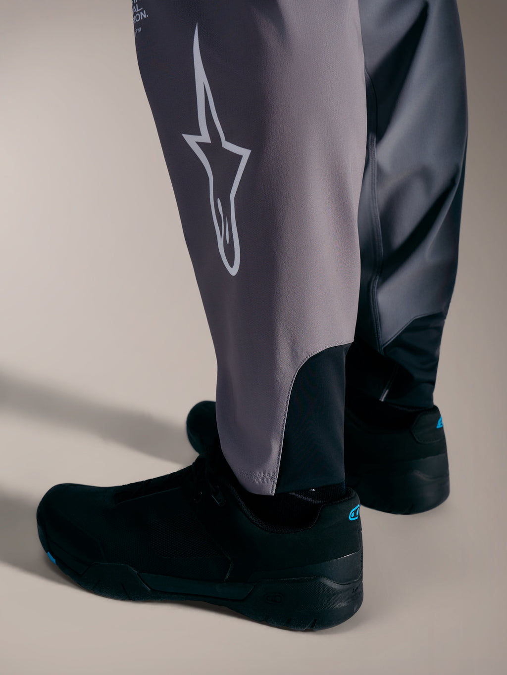 Grijze A-Supra Elite-broek met wit Astars-logo en stretchmanchetten voor prestatiegerichte MTB-races.