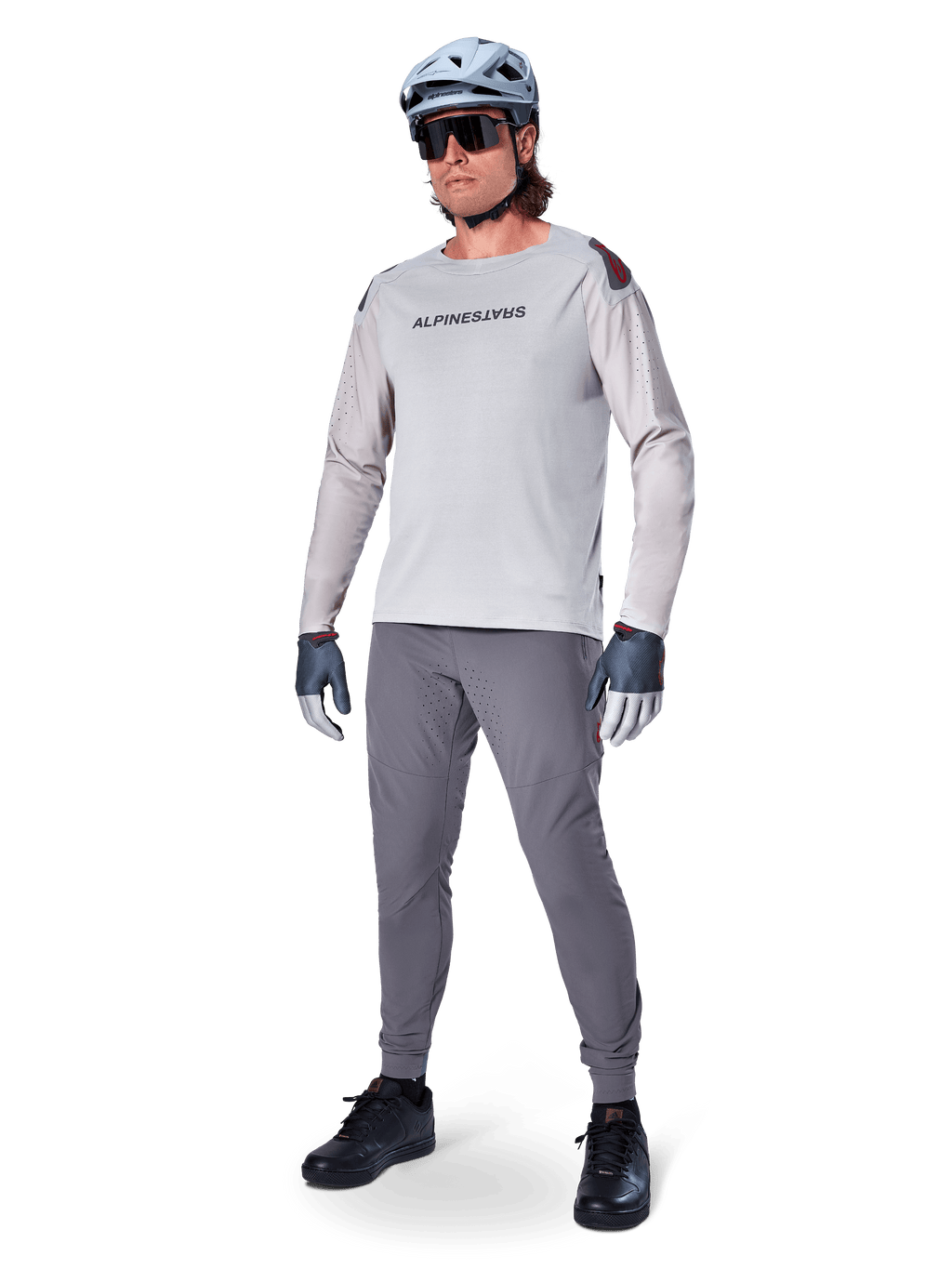 Pantalon Alpinestars A-Aria Elite, pantalon de VTT gris foncé, porté par un cycliste avec un maillot à manches longues gris clair et un casque gris, doté de ventilations découpées au laser sur les cuisses et d'une coupe performance ajustée pour le VTT