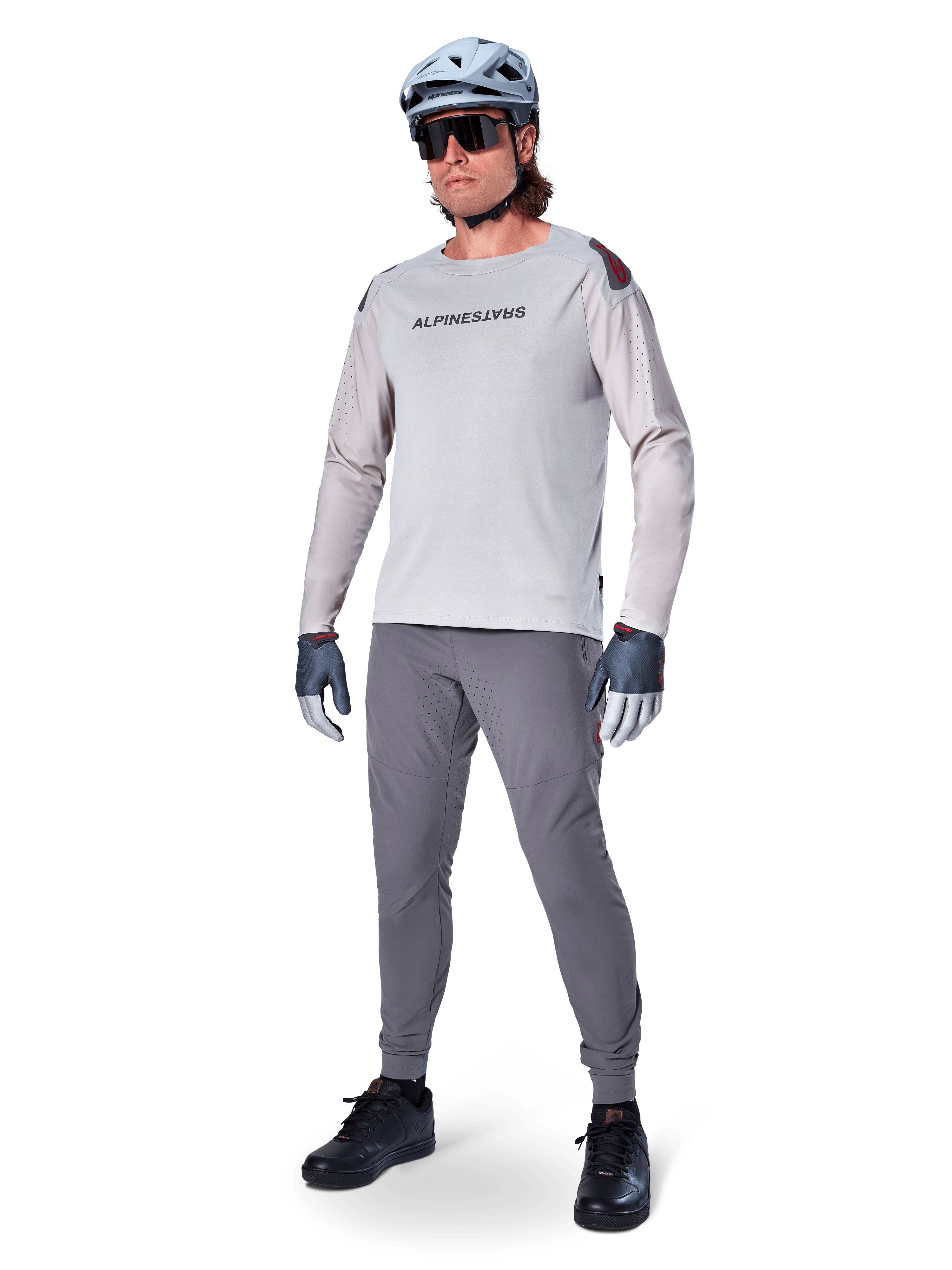 Pantalon Alpinestars A-Aria Elite, pantalon de VTT gris foncé, porté par un cycliste avec un maillot à manches longues gris clair et un casque gris, doté de ventilations découpées au laser sur les cuisses et d'une coupe performance ajustée pour le VTT