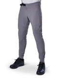 Alpinestars A-Aria Elite Pants, pantalon de VTT gris foncé, panneaux perforés au laser sur les cuisses, fermeture à boucle magnétique noire, poche zippée, détail de logo rouge, coupe performance ajustée, porté avec des chaussures noires