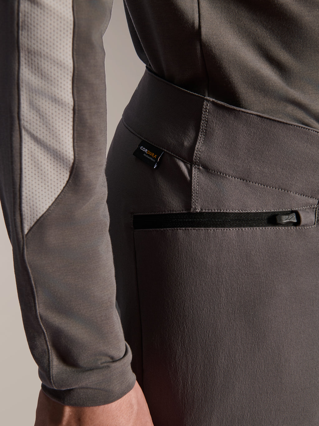 Alpinestars A-Dura Elite Pants, donkergrijze mountainbikebroek, close-up detail van zijzak met ritssluiting en Cordura-stoflabel, duurzaam 4-way stretch textiel voor off-road prestaties