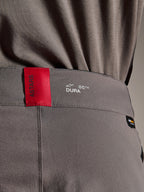 Alpinestars A-Dura Elite Pants, MTB-broek, donkergrijs, close-up van de tailleband met een rood ASTARS-label en wit DURA-logo, voorzien van getextureerde Cordura-stof en hoogwaardige brandingdetails.