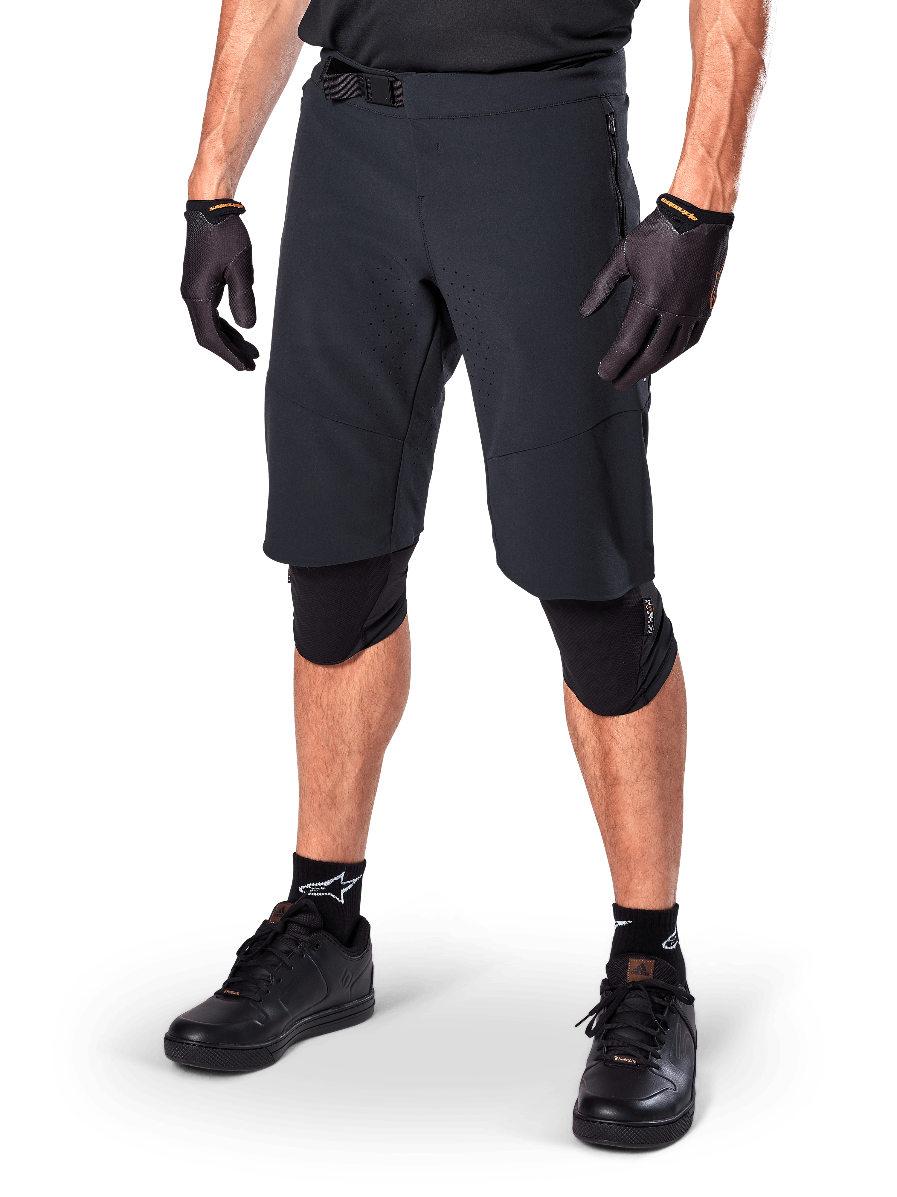 Alpinestars A-Aria Elite Shorts, zwarte mountainbike broek, gedragen met bijpassende zwarte handschoenen en kniebeschermers, voorzien van een magnetische gesp en lasergesneden perforaties, strak ontwerp voor off-road mountainbiken